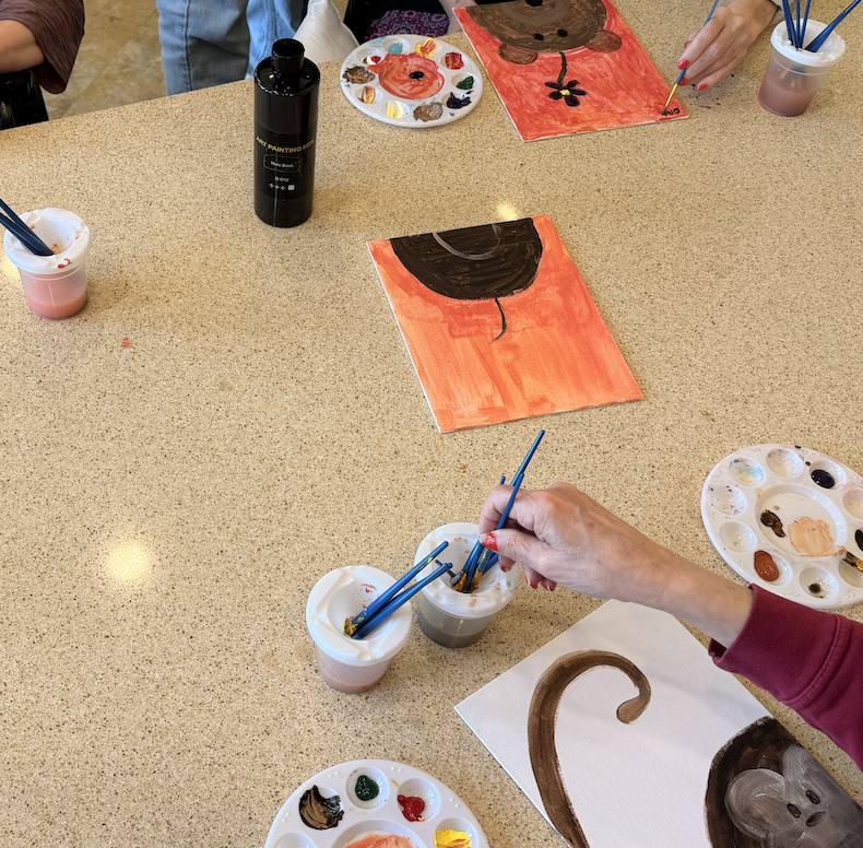 Workshop table with palettes, rinsing cups, and paintings in progress.