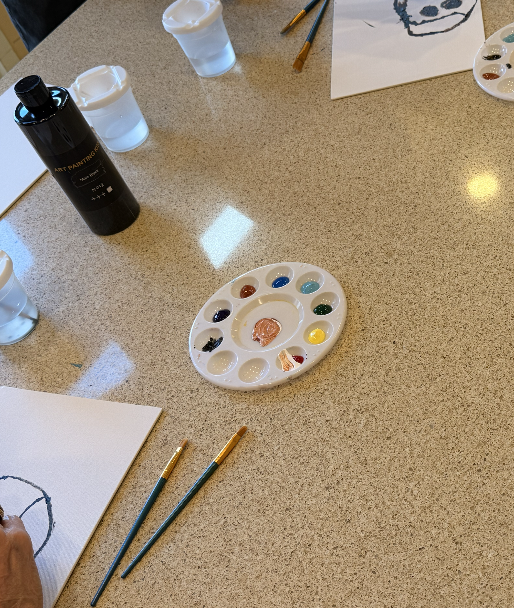 Paint palette and brushes laid out across a workshop table.