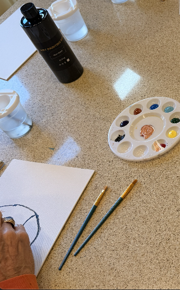 Workshop table with brushes, palette, and an early sketch on canvas.
